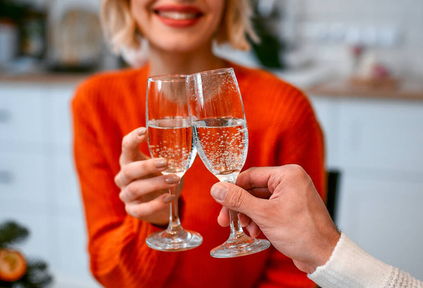 Hyvää joulua ja onnellista uutta vuotta! Söpö nainen clinks lasit samppanjaa poikaystävänsä kanssa tehdessään uudenvuoden paahtoleipää. - Valokuva, kuva