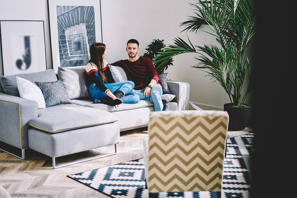 Male and female best friends have live meeting in stylish living room for talking about date bonding, young Caucaisan marriage resting at comfortable sofa recreating during pastime weekend - Fotografie, Obrázek