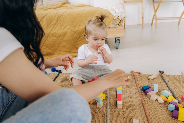 Early childhood development. Communication between mother and child. Love and kindness in the family. The kid plays with wooden eco-friendly toys. - Фото, изображение