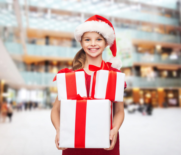 smiling little girl in santa helper hat with gifts - Photo, image