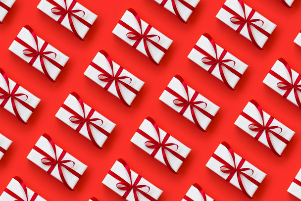 Patrón con cajas de regalo blancas sobre fondo rojo. Vista superior, plano. - Foto, Imagen