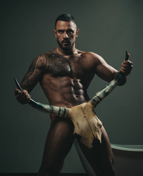 Man with naked torso, muscle, strong body. Halloween bull horn. Sexy gay with erotic masculine, body six pack hold bull horns. - Фото, зображення