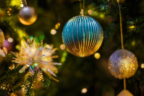 Christmas balls on a branch of a pine tree and a blurred dark background with colorful bokeh. Soft focus. Copy space. - Photo, Image