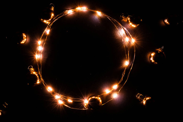 Рождественские огни границы. Золотая световая гирлянда, золотая лампочка на черном фоне для украшения новогодней вечеринки. Светящиеся огни на Рождество - Фото, изображение