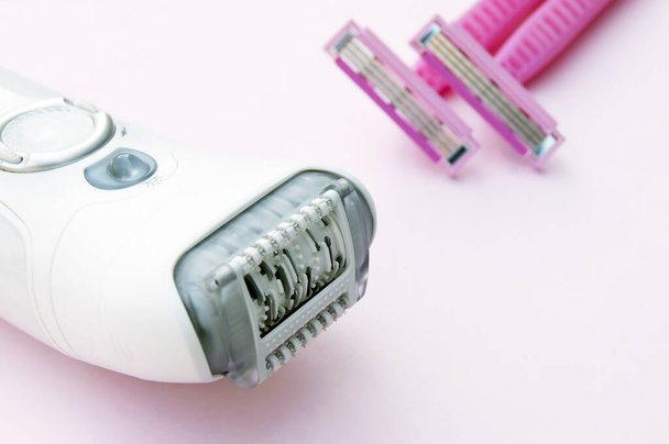 White epilator and pink razor on a pink background. The concept of choosing a method of hair removal. - Fotografie, Obrázek