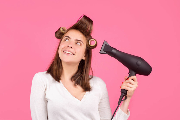 Smiling woman with hair dryer and rollers. Woman with hair dryer. Beautiful girl with straight hair drying hair with professional hairdryer. - Photo, image