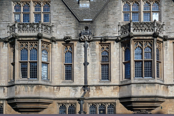 OXFORD, ENGLAND -  Gargoyles and leaded glass bay windows look out onto the street from one of the ancient Oxford colleges. - Photo, Image