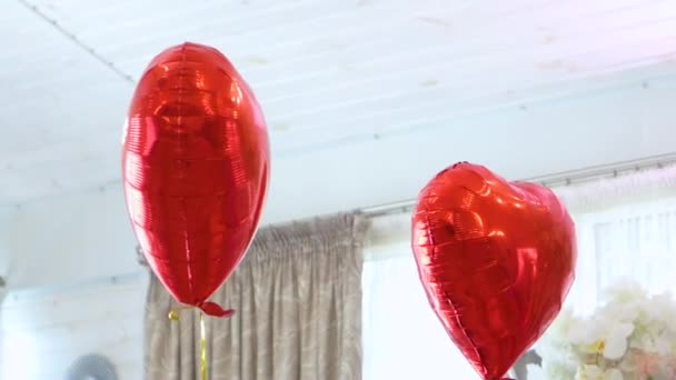 διακόσμηση της αίθουσας δεξιώσεων με λευκά τεχνητά λουλούδια και κόκκινα μπαλόνια σε σχήμα καρδιάς - Πλάνα, βίντεο