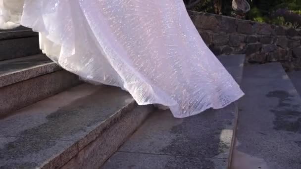 De bruid in een witte jurk loopt de granieten trap op. - Video
