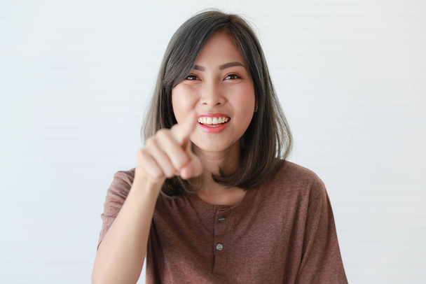 Studio portret zdjęcia Azji szczęśliwy młody piękny dość pewny siebie nastolatka nastolatka model w casual nosi uśmiechnięty śmiech pokazać zęby patrzeć na aparat wskazując palcem wskazującym na białym tle. - Zdjęcie, obraz