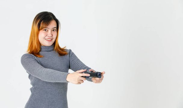 Portret close-up studio schot van Aziatische jonge tiener vrouwelijke model gamer in grijs coltrui jurk staande glimlachen met 3d video game dualshock console joystick in handen spelen op witte achtergrond. - Foto, afbeelding