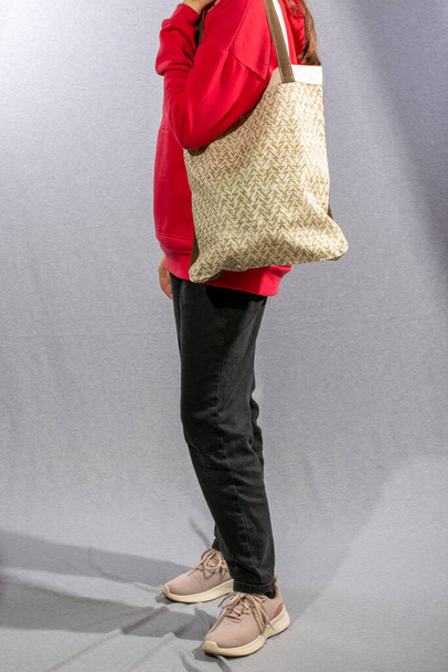 Дівчина тримає в руках багаторазовий еко сумку з натуральних тканин
 - Фото, зображення