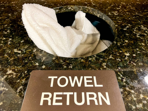 Een gebruikte witte handdoek op een granieten handdoek retourneert. - Foto, afbeelding