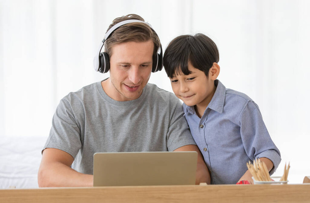 běloch otec pomáhá svému malému dítěti se školním domácím úkolem pomocí notebooku během online společného studia doma. Koncept online učení pro děti. - Fotografie, Obrázek
