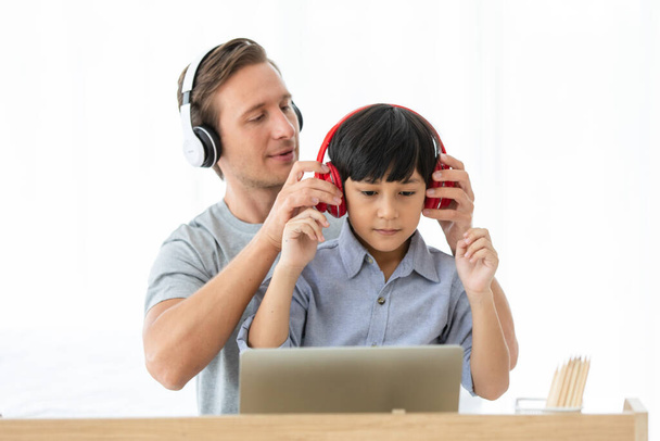 Kaukasische vader het helpen van zijn jonge kind met school huiswerk met behulp van laptop tijdens online studeren samen thuis. Concept online leren voor kinderen. - Foto, afbeelding