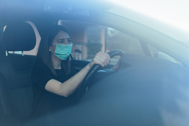 A Caucasian female in a face mask driving a car - Foto, Imagen