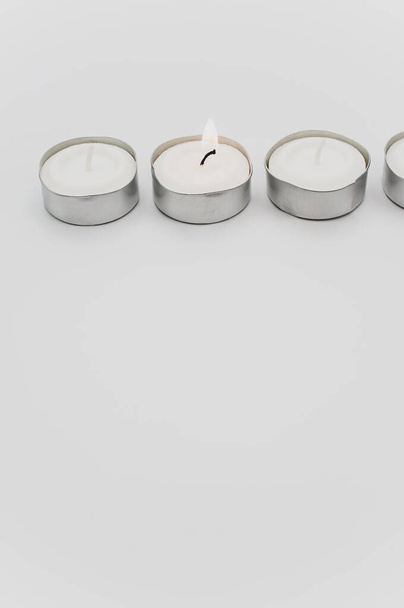 row of white scented wax tea lights on a white tabletop with copy space - Foto, afbeelding