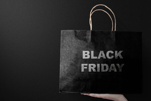 Women holding a shopping bag with a black background. Black Friday concept - Foto, afbeelding