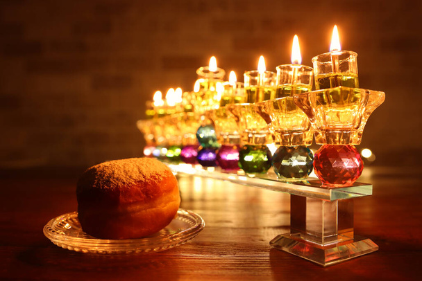 image of jewish holiday Hanukkah background with crystal menorah (traditional candelabra) and oil candles - Photo, image