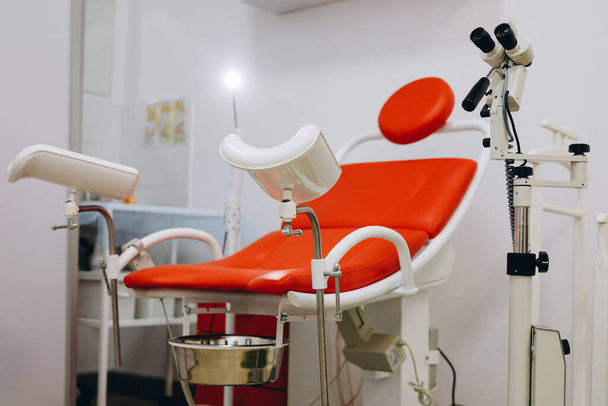 Foto de la nueva silla ginecológica roja de pie en un gabinete del hospital - Foto, Imagen
