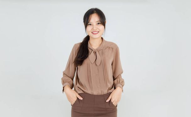 Ihana aasialainen tyttö hymyilee iloisesti ystävällisenä tunteena ja luottavaisena seistessään onnellinen kasvot ja houkutteleva viehättävä ruskea pusero melko rento asu naisten elämäntapaan - Valokuva, kuva