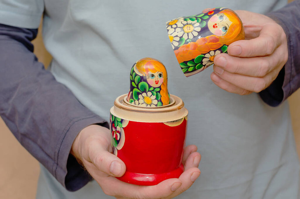 Ein erwachsener Mann mit einer hölzernen Matrjoschka-Puppe. Ein unverdecktes traditionelles russisches Spielzeug. Symbol Russlands. Selektiver Fokus. - Foto, Bild