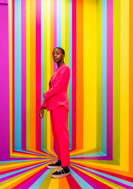 Beautiful african american young woman dancer having fun inside a rainbow box room - Cool and stylish afro adult woman portrait on multicolored background, influencer creating content for social networks in a selfie room - 写真・画像