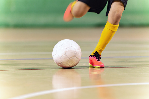 Κοντινό πλάνο Εικόνα του Futsal Player Kicking Ball. Εσωτερική μπάλα ποδοσφαίρου κλωτσιά. Εσωτερικός εξοπλισμός ποδοσφαίρου. Τζούνιορ ποδοσφαιριστής Running και κλοτσιές μπάλα - Φωτογραφία, εικόνα