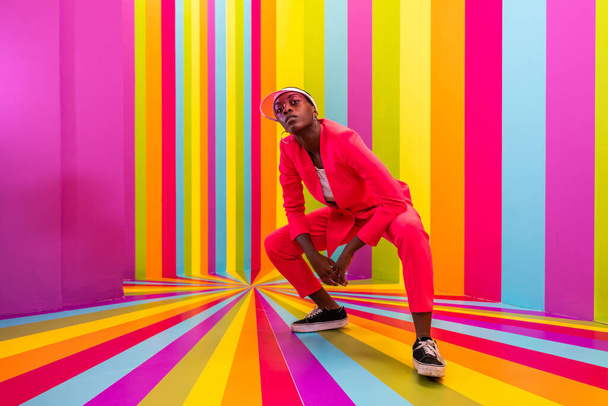 Beautiful african american young woman dancer having fun inside a rainbow box room - Cool and stylish afro adult woman portrait on multicolored background, influencer creating content for social networks in a selfie room - Photo, image