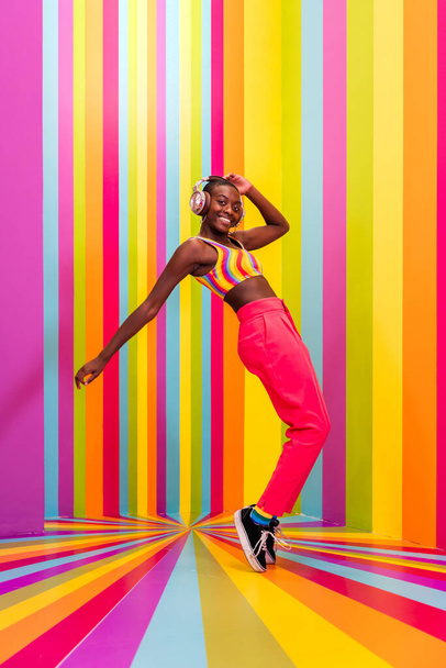 Beautiful african american young woman dancer having fun inside a rainbow box room - Cool and stylish afro adult woman portrait on multicolored background, influencer creating content for social networks in a selfie room - Foto, Bild