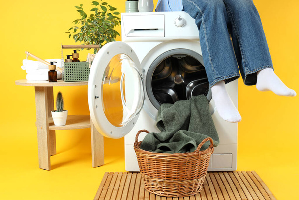 Concept of housework with washing machine and girl on yellow background - Foto, Imagem