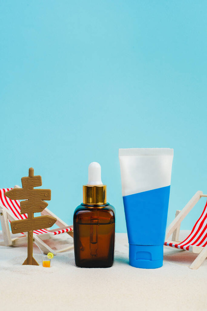 Summer sunscreen cream banner ads. Beach holiday cosmetics. Sun cream and sun essence. Unisex cosmetics. Concept photo of relaxing on the beach. Deck chairs on the sand on a blue background. Mockup  - Photo, image