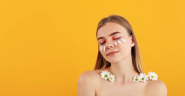 Gyönyörű modell lány virágokkal sárga háttér - Fotó, kép