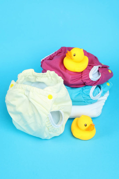 Concepto de ropa de bebé con pañales reutilizables sobre fondo azul - Foto, Imagen