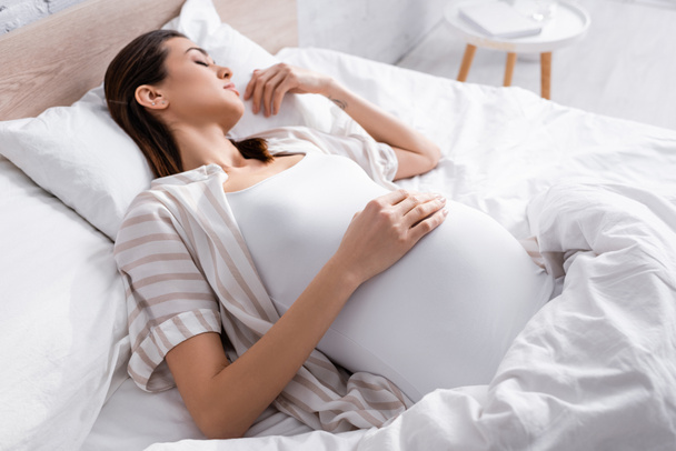 high angle view of pregnant woman sleeping in bed - Photo, Image