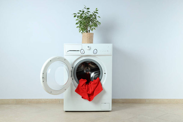 Concept of housework with washing machine against white wall - Foto, imagen