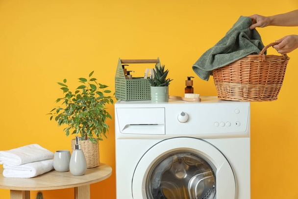 Conceito de trabalho doméstico com máquina de lavar roupa no fundo amarelo - Foto, Imagem
