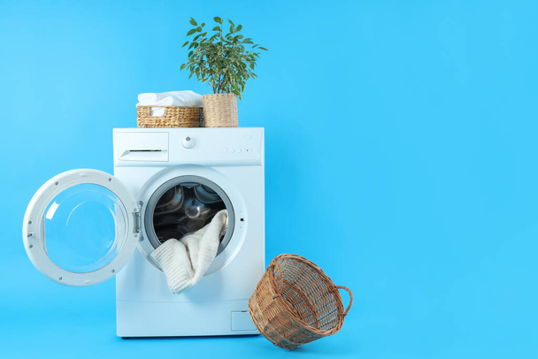 Concepto de tareas domésticas con lavadora sobre fondo azul - Foto, Imagen