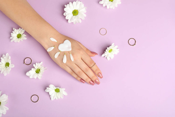 Konzept der Handpflege auf lila Hintergrund mit Blumen - Foto, Bild