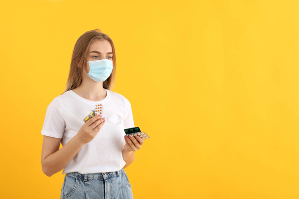 Ragazza malata in maschera con pillole su sfondo giallo - Foto, immagini