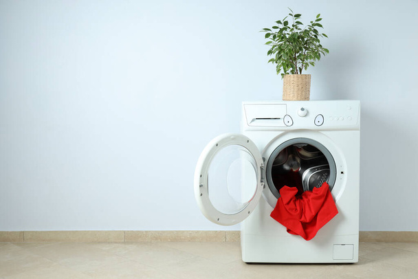 Concept of housework with washing machine against white wall - Foto, afbeelding