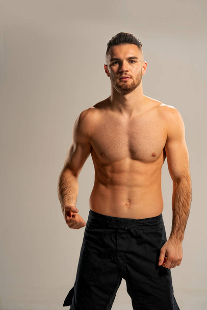 MMA bojovník v černých kraťasech pózovat na šedém pozadí - Fotografie, Obrázek