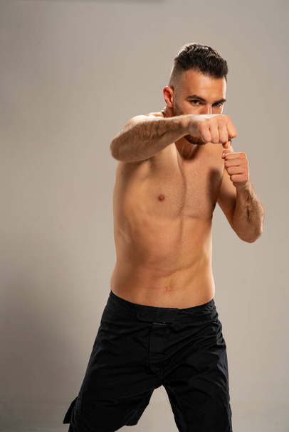 MMA fighter w czarnych szortach w pozycji bojowej na szarym tle - Zdjęcie, obraz