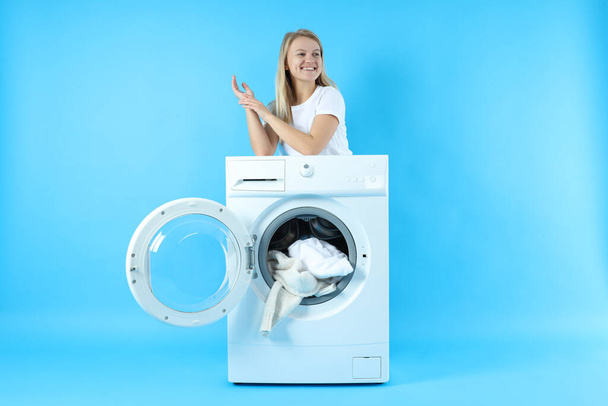 Concept of housework with washing machine and girl on blue background - Valokuva, kuva