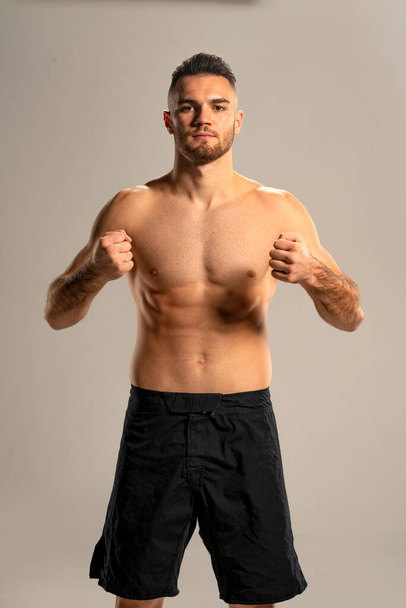 MMA bojovník v černých kraťasech pózovat na šedém pozadí - Fotografie, Obrázek