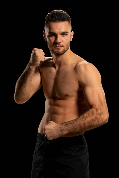Боєць MMA в чорних шортах, що поставляються на чорному тлі - Фото, зображення