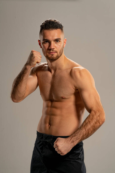 MMA taistelija mustissa shortseissa poseeraa harmaalla taustalla - Valokuva, kuva