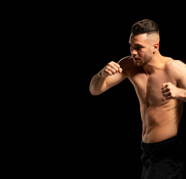 MMA fighter in black shorts in a fighting position on a black background - Фото, изображение
