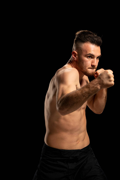 Боєць MMA в чорних шортах у бойовому положенні на чорному тлі - Фото, зображення