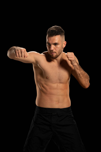 MMA fighter in black shorts in a fighting position on a black background - Photo, Image